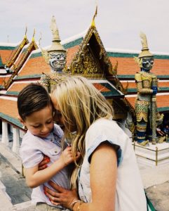 young mom and little child hugging in front of the grand palace in Thailand to show how to have fun and learn while traveling