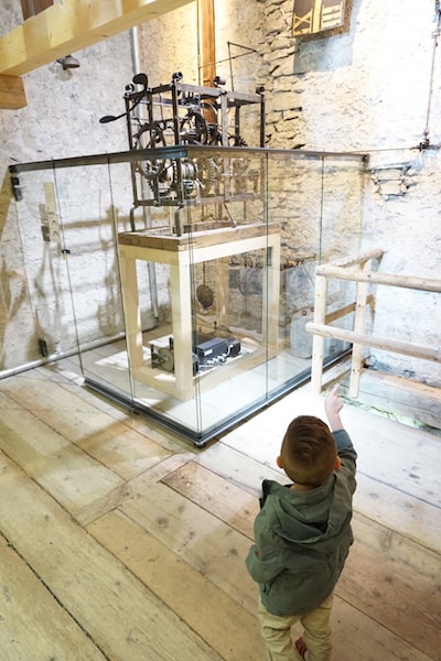 a toddler examining old gears of a machine.