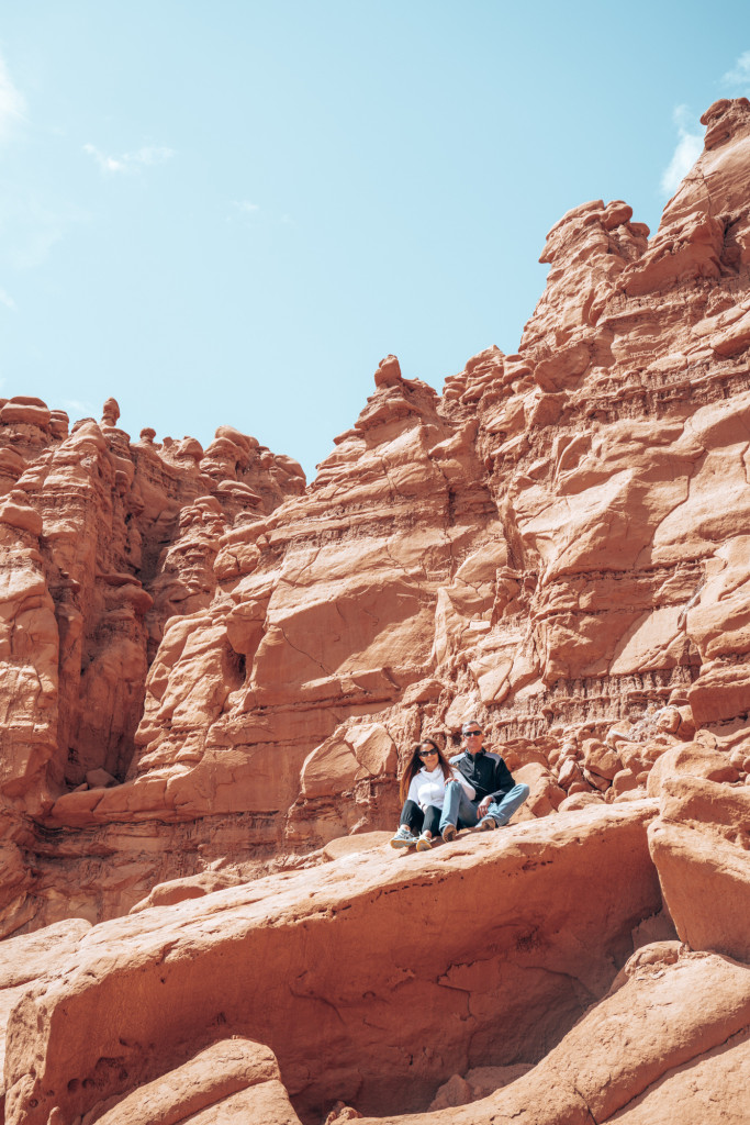 A man and a women sit on a large red rock in Southern Utah.