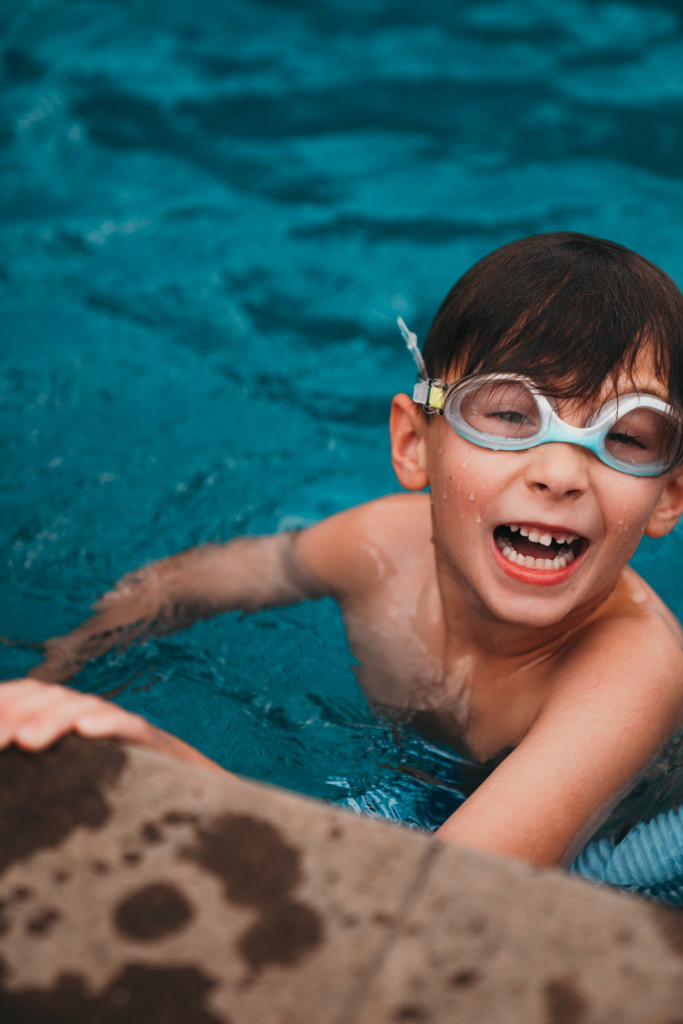 A little boy swims in a backyard swimming pool.