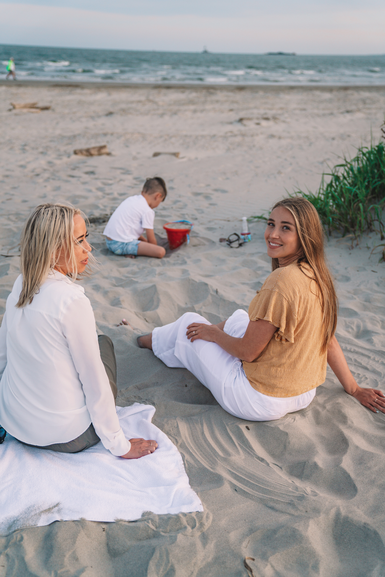 charleston sc visitors guide - two sisters and a little boy sit on the beach and play in the sand. 