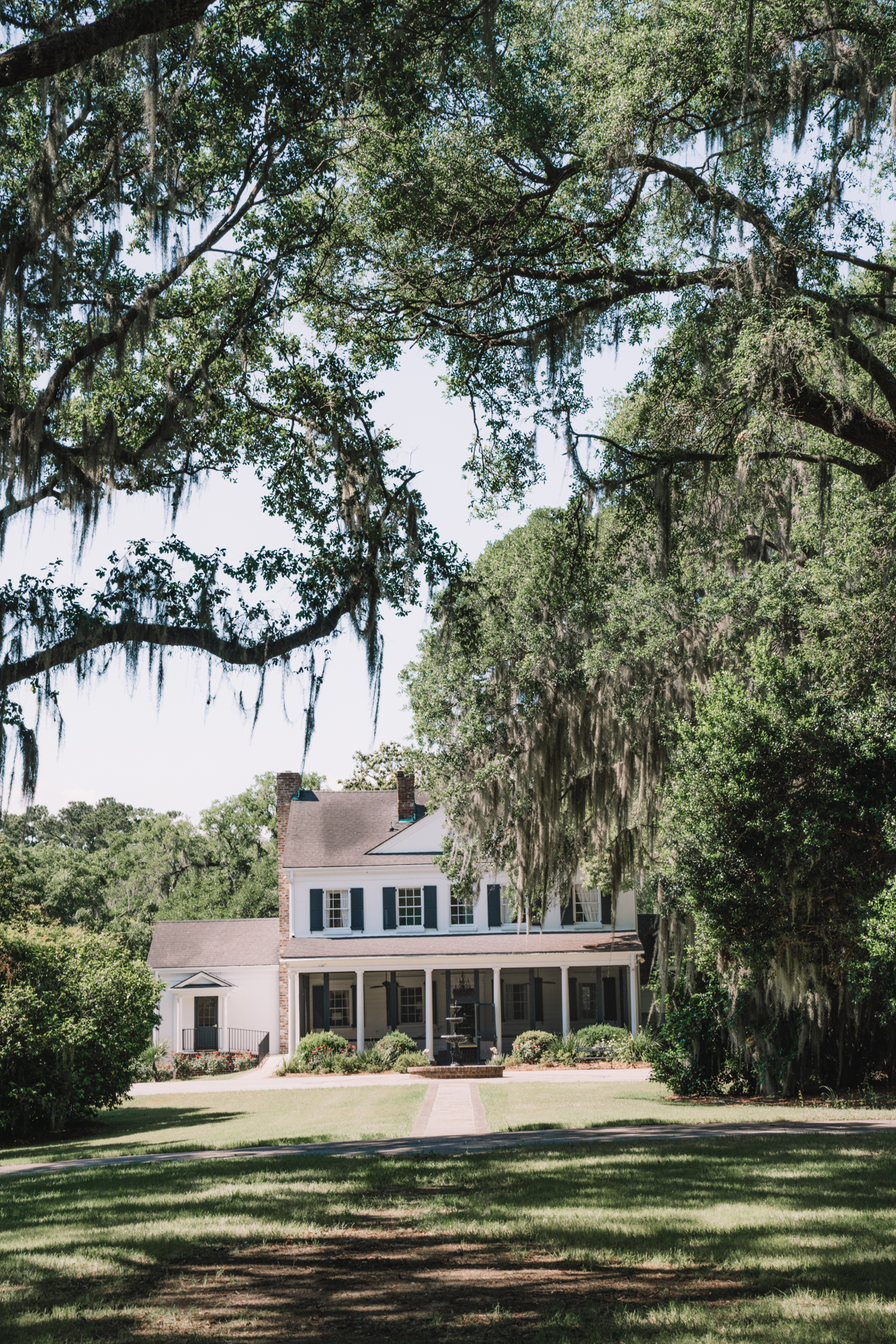 Things to do in Charleston sc with kids - a white plantation house with black shutters stands beneath oak trees hanging Spanish moss.