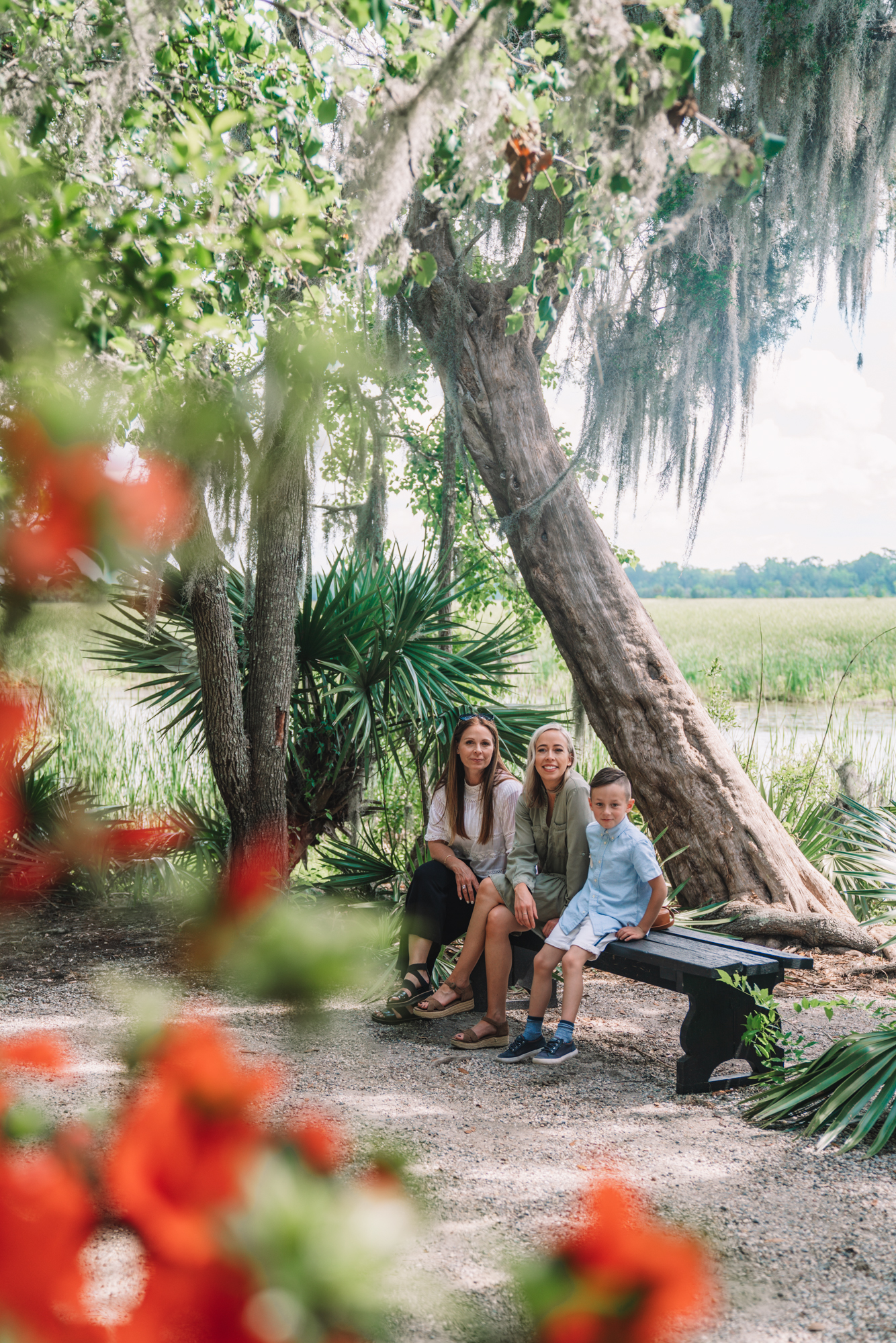 Things to do in Charleston sc with kids - a family sitting on a bench with tupelo trees with spanish moss hanging. 