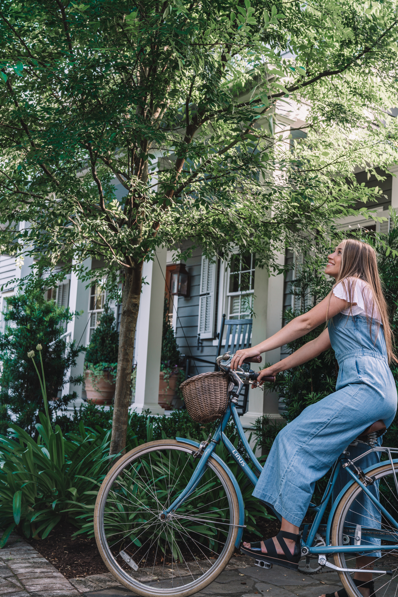 charleston sc visitors guide - a women sits on a blue bike in front of a blue southern home. 