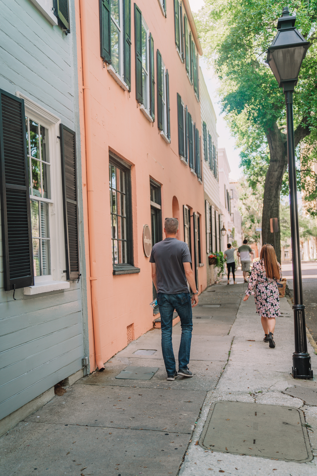 charleston sc visitors guide - a man and a women walk in front of the brightly colored souther houses in Charleston