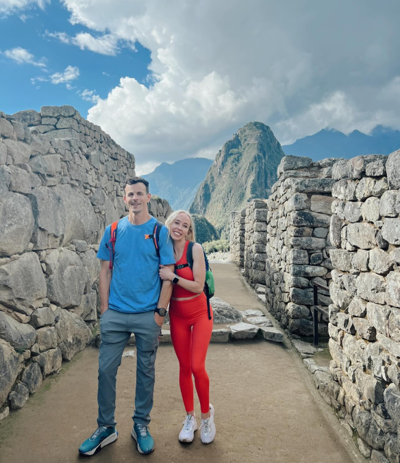 Kam and husband hiking through ancient stone ruins at Machu Picchu Peru with mountain peaks