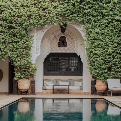 Moroccan riad courtyard with reflecting pool and traditional archways covered in vines