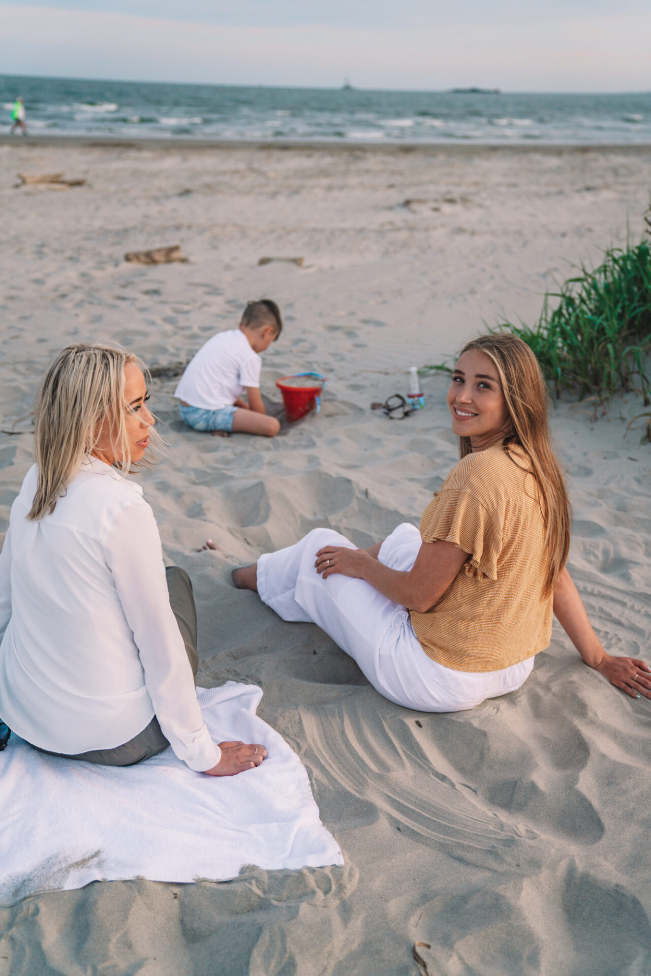 charleston sc visitors guide - two sisters and a little boy sit on the beach and play in the sand.