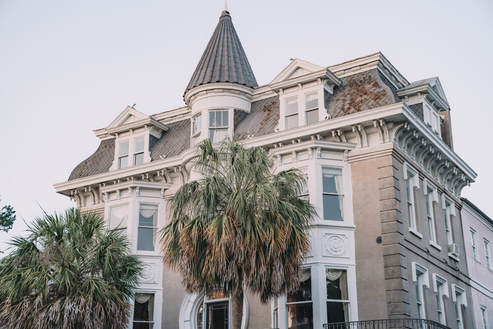 charleston sc visitors guide - a giant antebellum house with palmetto trees in front.