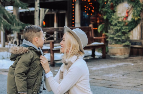 mother tightens up kids coat to keep him warm on winter´s trip