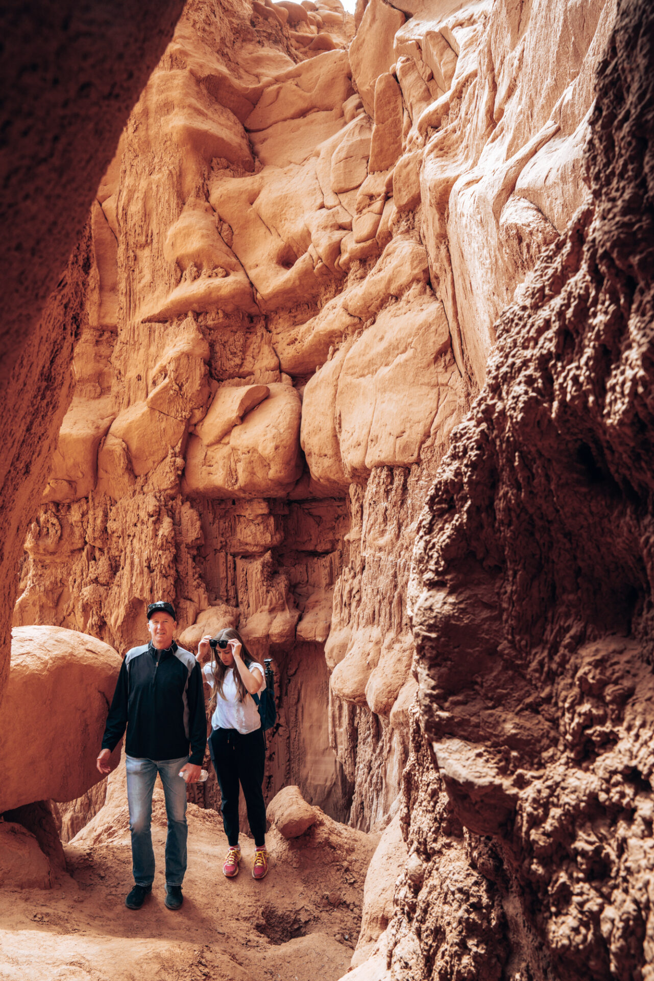 A older man and his adult daughter hike along the slot canyons in red rocks of souther utah.