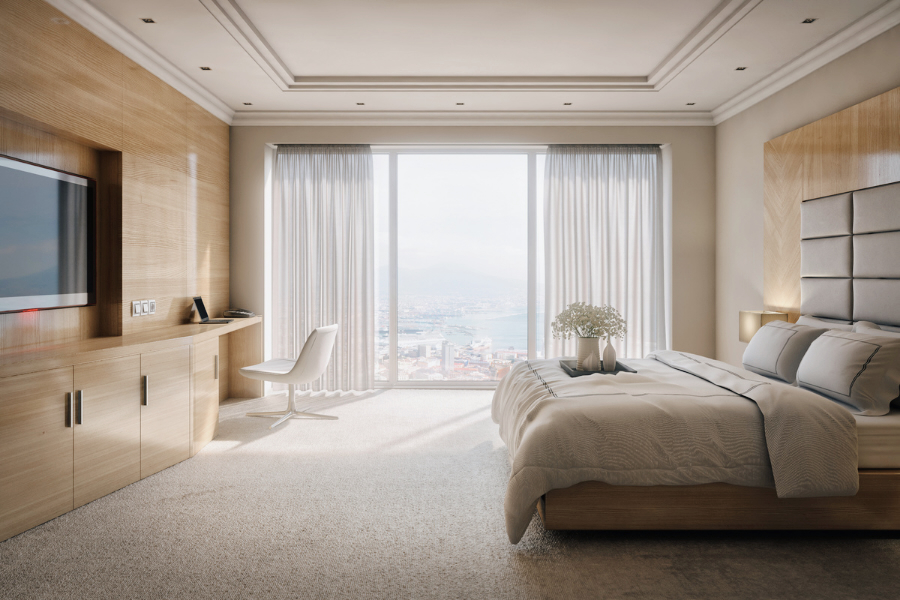 Elegant hotel bedroom with floor to ceiling windows overlooking ocean and city skyline