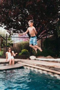 kid jumping on the pool with family
