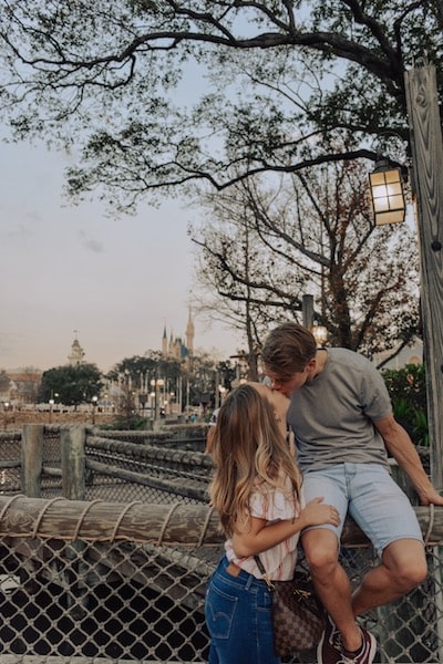a young couple kissing without kids at disneyworld on a bridge