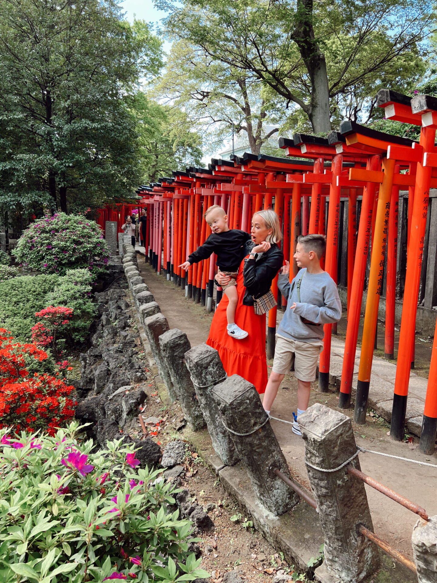 Family walking through tunnel of red torii gates at Fushimi Inari shrine in Japan