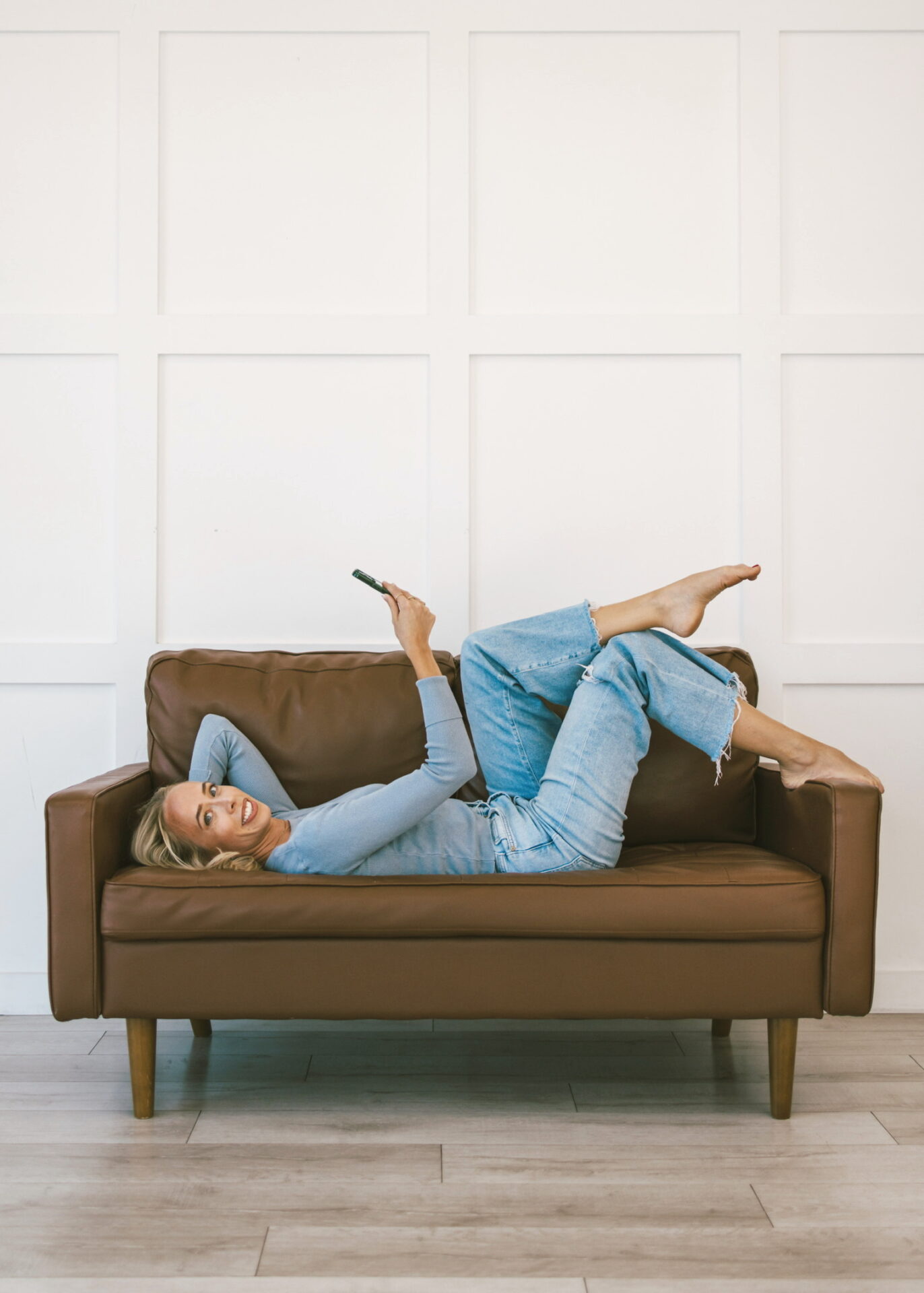 Kam lying on tan couch reading book in comfortable casual outfit