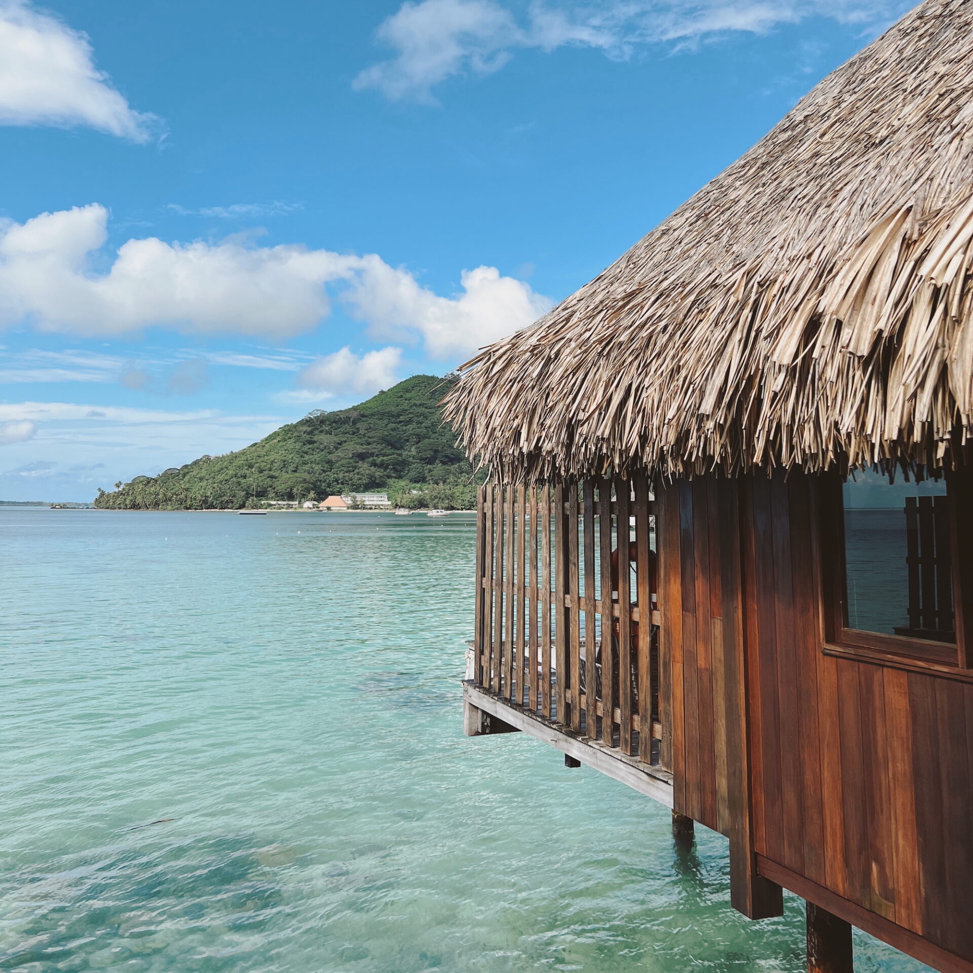Luxury overwater bungalow with thatched roof on turquoise tropical lagoon