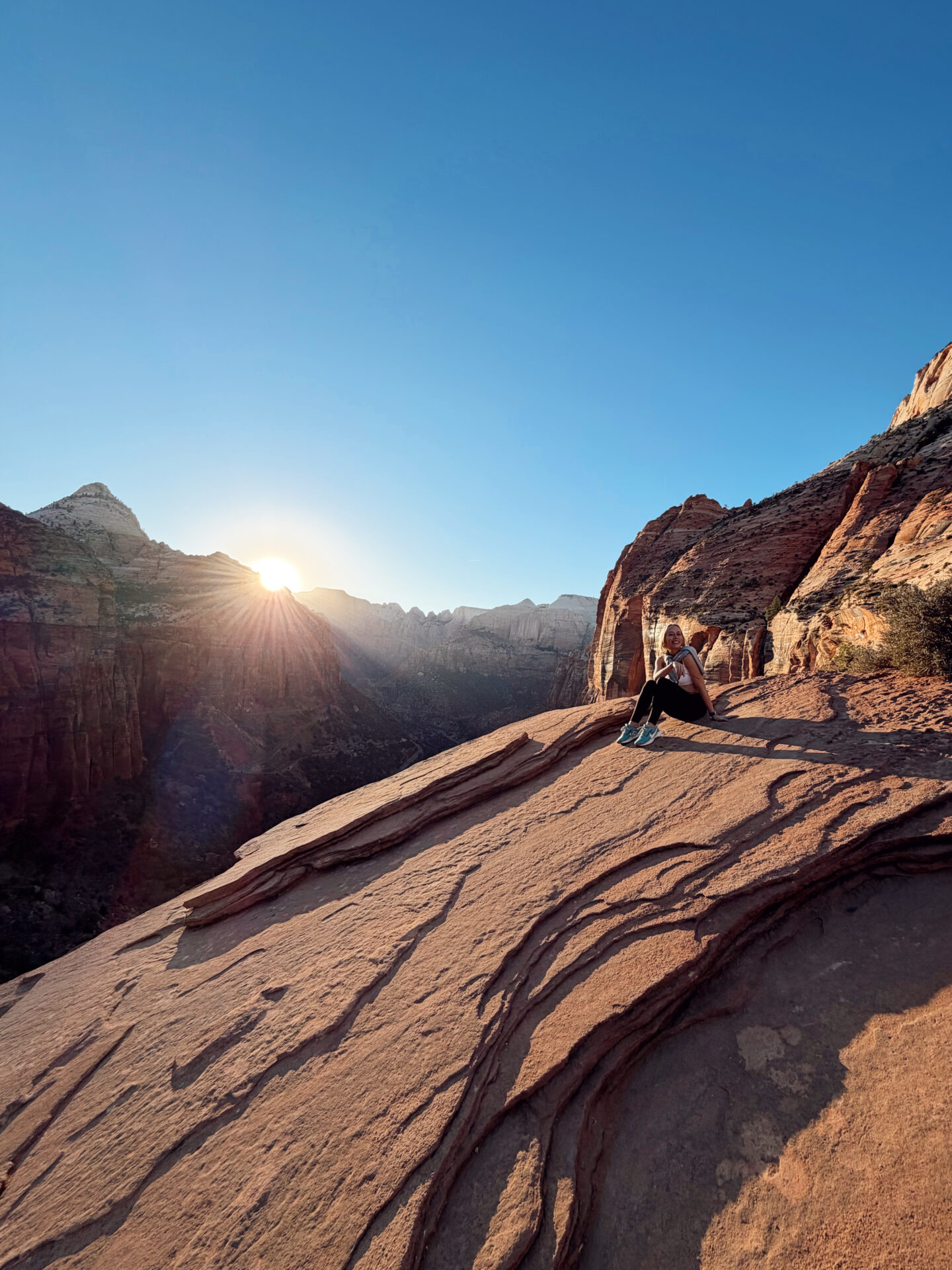 Woman watching the sunset from the Canyon Overlook Trail with panoramic views of Zion Canyon below