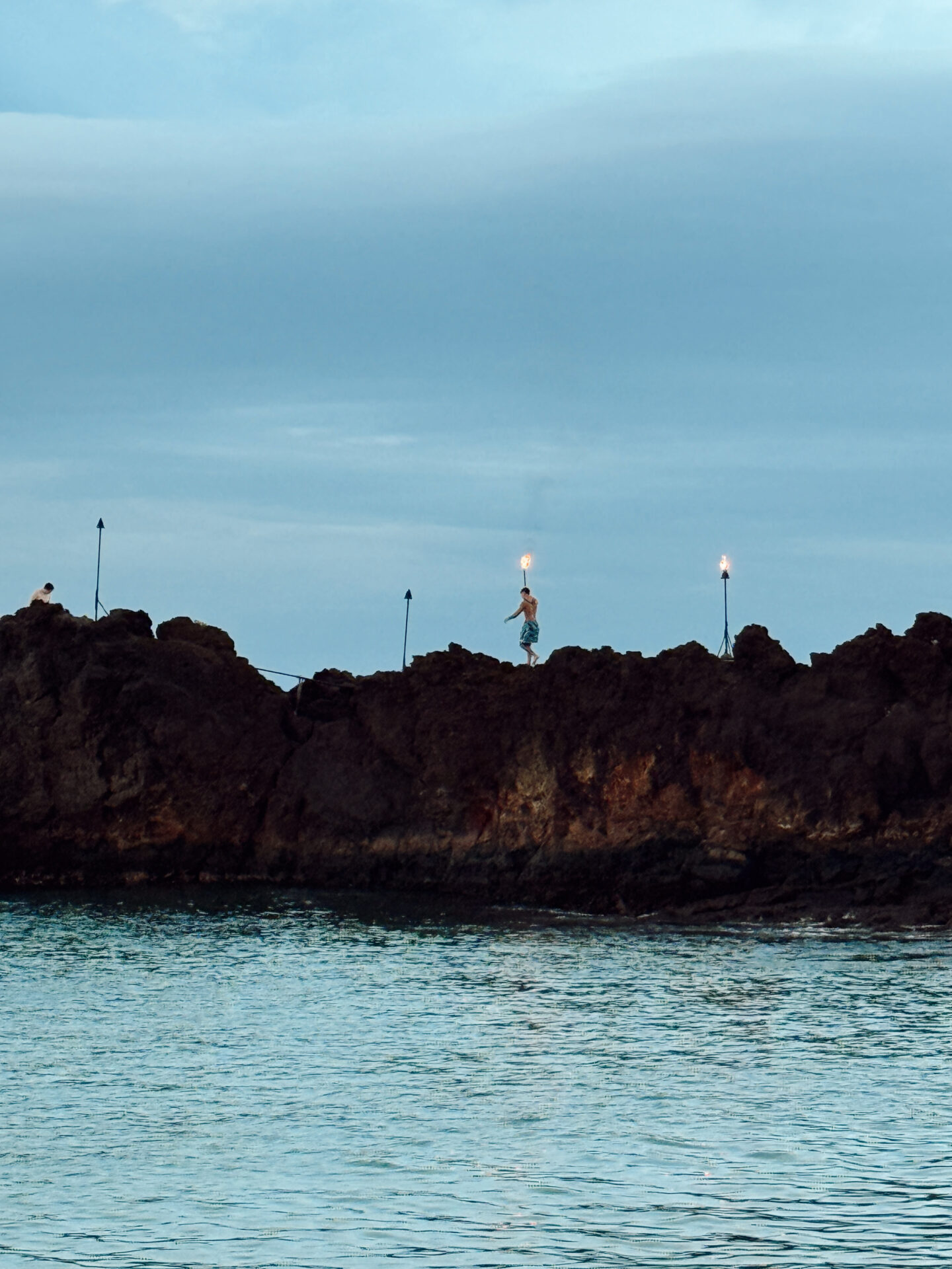 Torch lighting ceremony on Black Rock cliff at Ka'anapali Beach in Maui at dusk