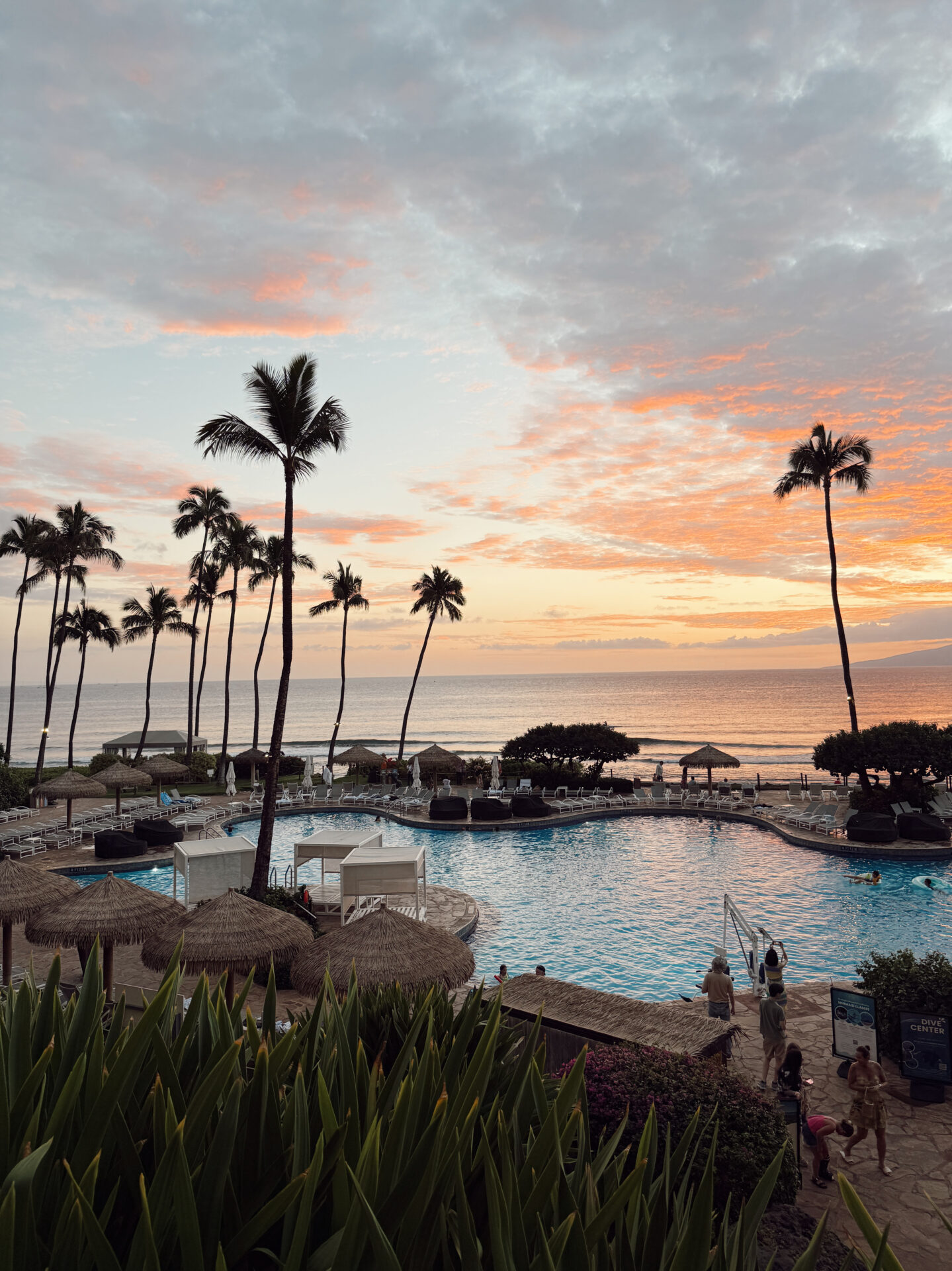 Hyatt Regency Maui pool area at sunset with palm trees tiki umbrellas and Pacific Ocean views