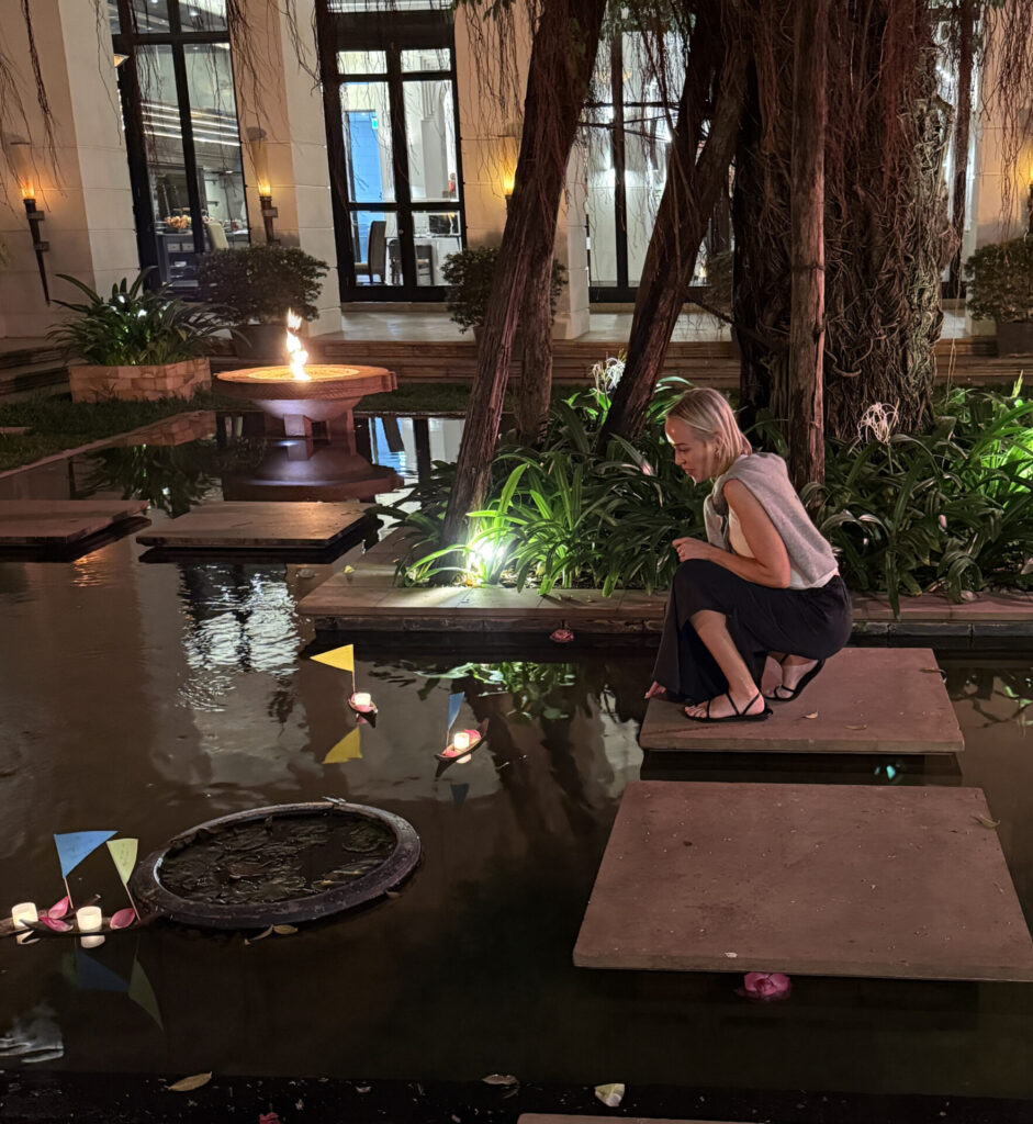Guest watching floating candle boats during the evening Buddhist wishing ceremony at Park Hyatt Siem Reap courtyard