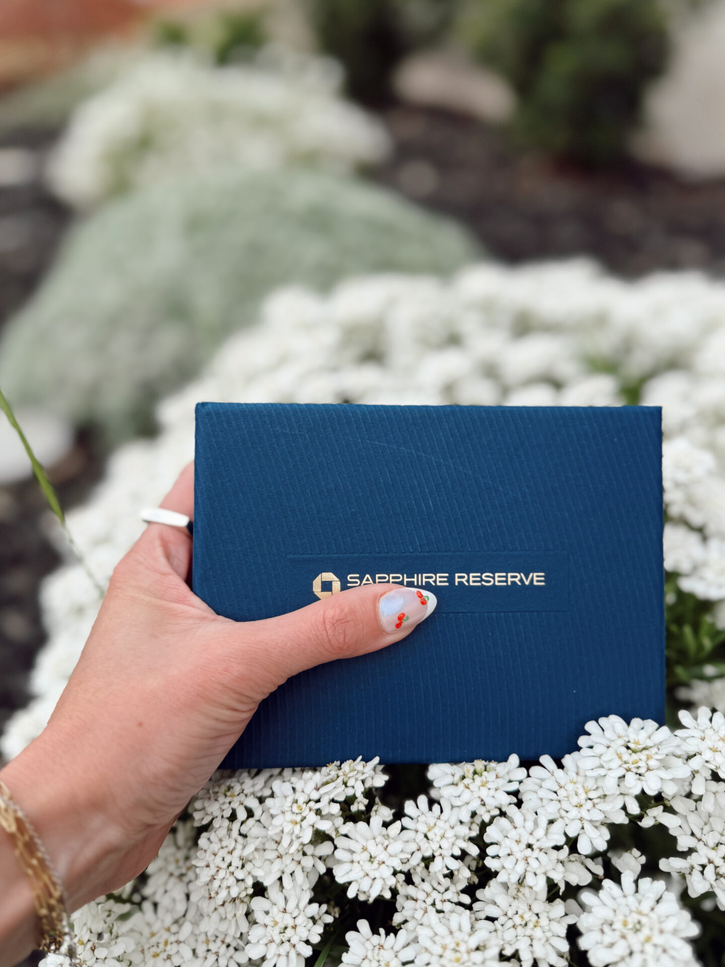 Chase Sapphire Reserve card packaging held in front of white flowers