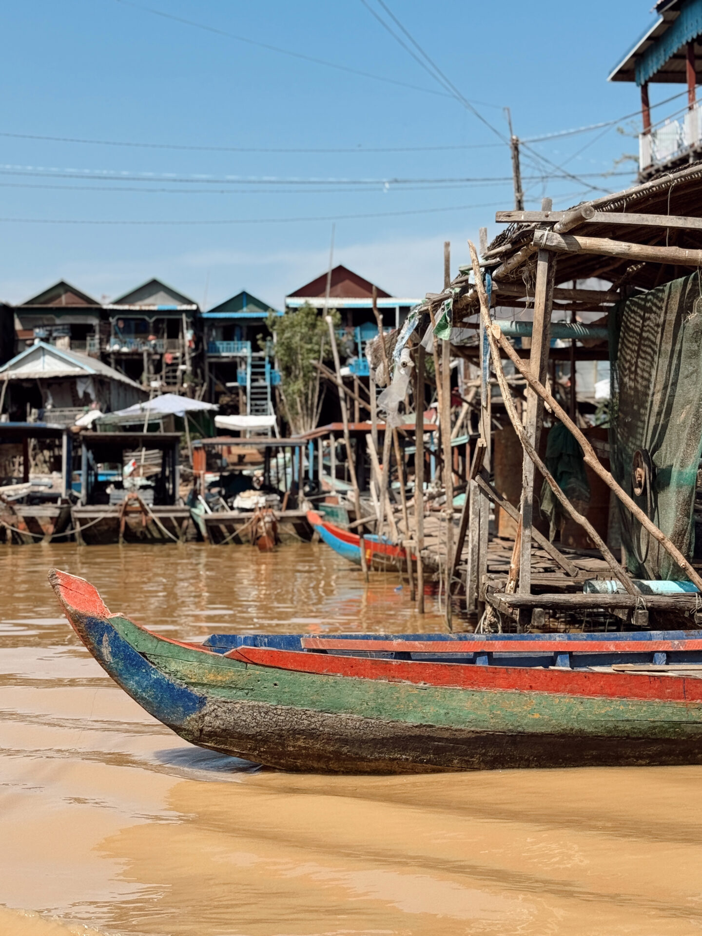 Colorful wooden boat at Kampong Phluk floating village with stilt houses along the waterway