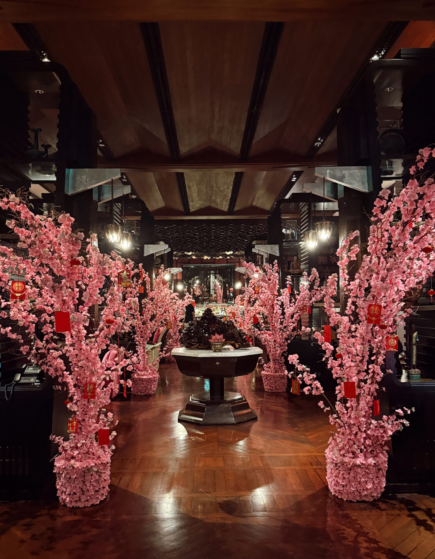 Park Hyatt Siem Reap lobby decorated with pink cherry blossom trees and red lanterns on dark wood floors