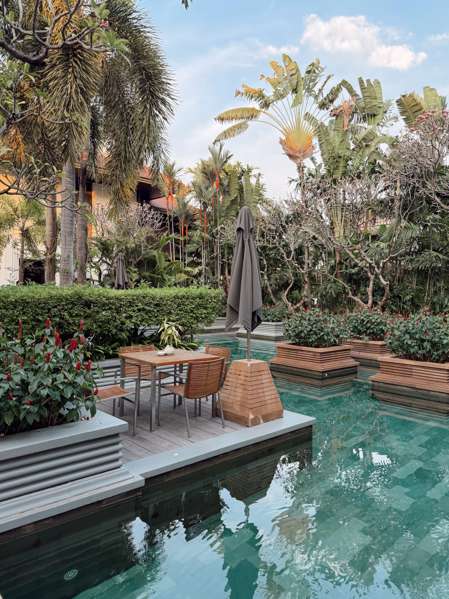 Poolside dining table surrounded by tropical plants and green-tiled pool at the Park Hyatt Siem Reap