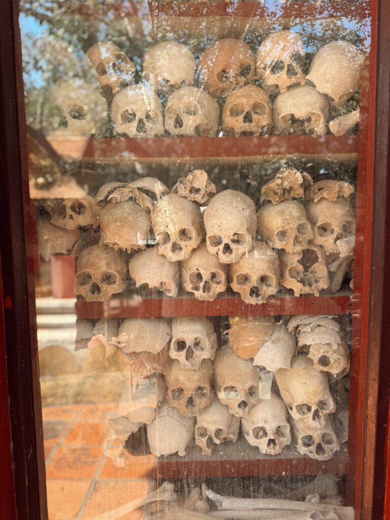 Rows of skulls displayed behind glass inside the Wat Thmey memorial stupa in Siem Reap