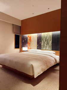 King bed and backlit Japanese floral headboard in a guest room at the Hyatt Regency Kyoto.