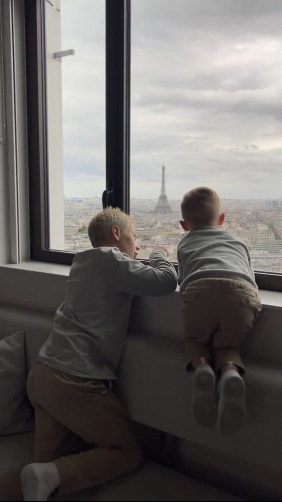 Two young boys looking out a high-rise window toward the Eiffel Tower at the Hyatt Regency Paris.