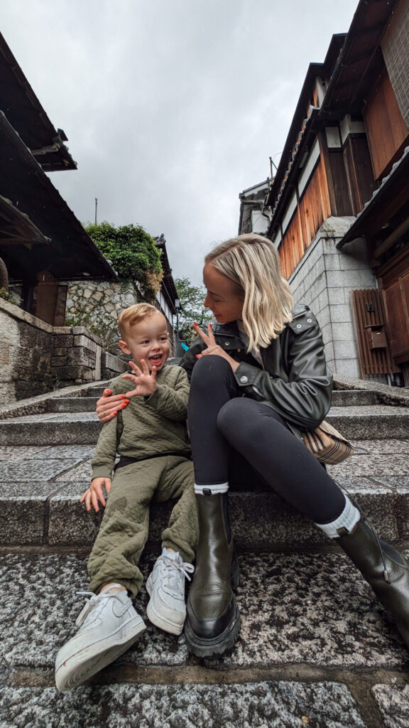 Mom and young son laughing on stone steps in a historic Kyoto neighborhood in Japan