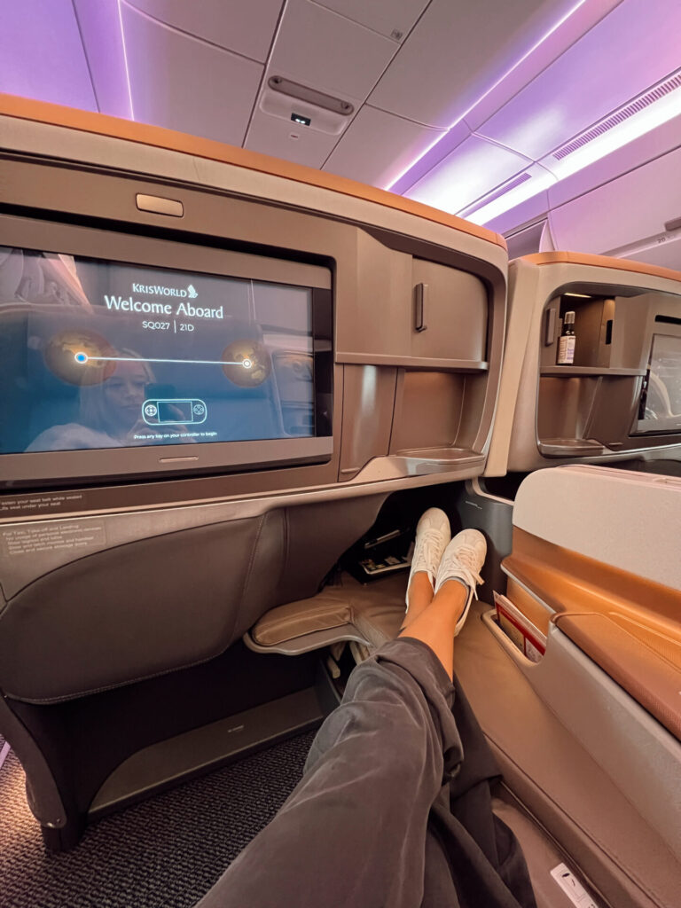 Singapore Airlines business seat reclined with the KrisWorld welcome screen on a flight to Asia