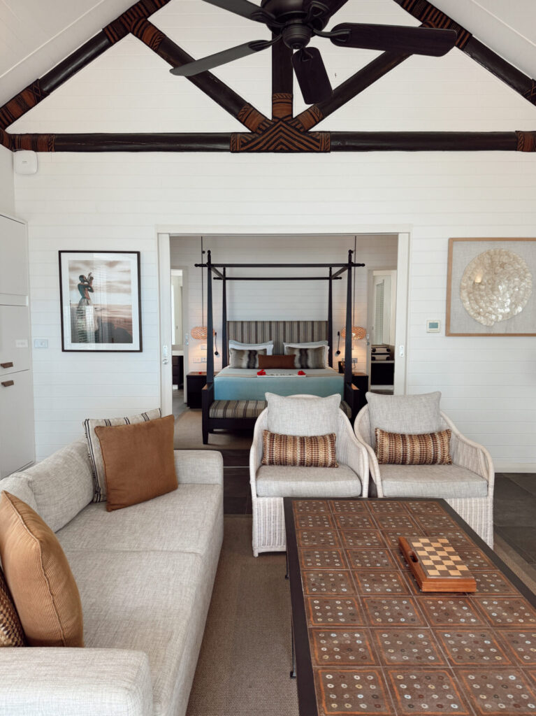 Spacious Fiji family villa with a four-poster bed, sitting area, and vaulted timber ceiling
