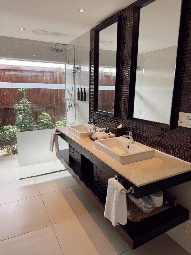 Sheraton Tokoriki villa bathroom with double vessel sinks and a walk-in rain shower opening to a private garden