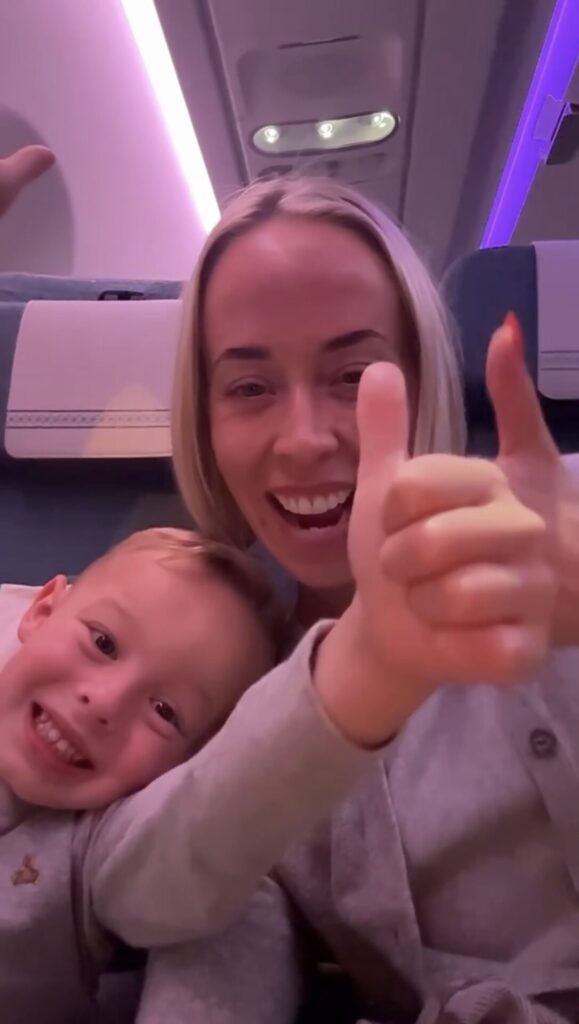 Mom and young son smiling and giving thumbs up on the flight, showing flying to Fiji with kids