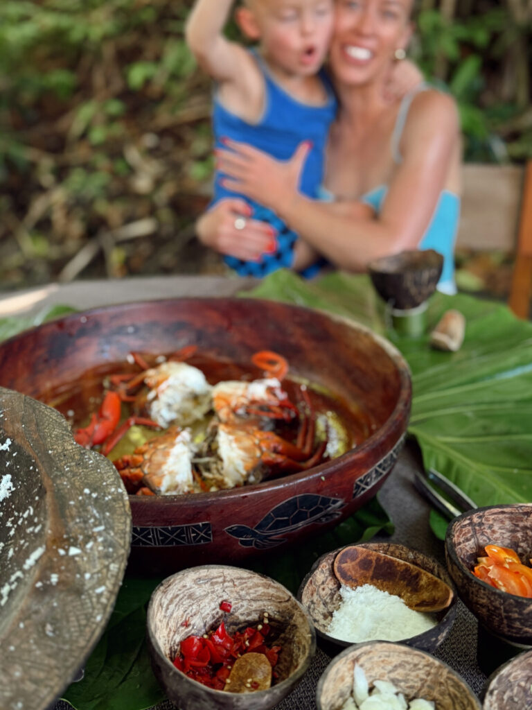 Traditional Fijian feast of mud crab and prawns in a carved wooden bowl with coconut-shell condiments