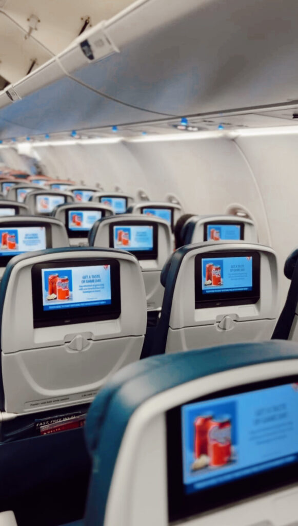 Rows of seatback entertainment screens in an airplane cabin on a flight booked with Capital One Venture miles