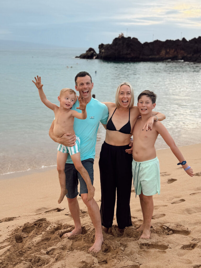 Family of four laughing on the beach near Black Rock at Ka'anapali, Maui