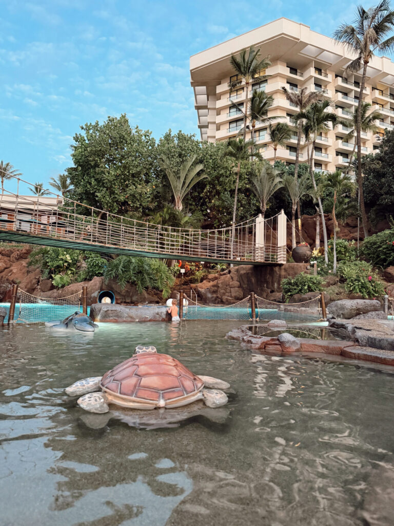 Sea turtle and manta ray statues in the lagoon pool at Hyatt Regency Maui, with the rope bridge behind