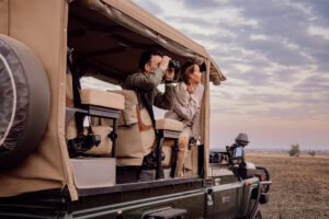 Couple watching wildlife from an open safari vehicle at sunrise in the Serengeti on a trip booked with Marriott points