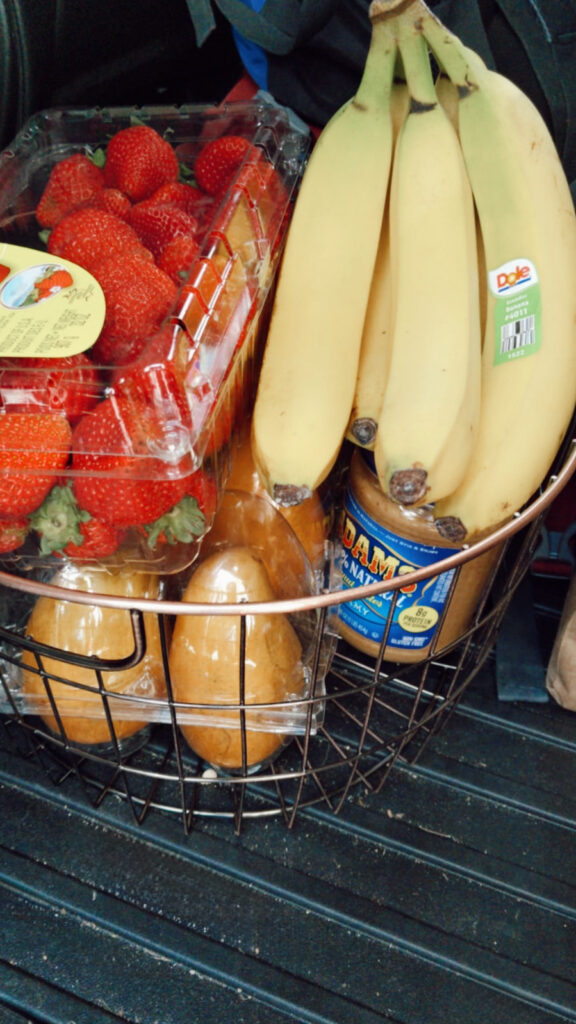 Fresh strawberries, bananas, and peanut butter in a wire grocery basket