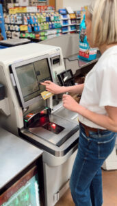 Woman using a credit card at a self-checkout kiosk while grocery shopping