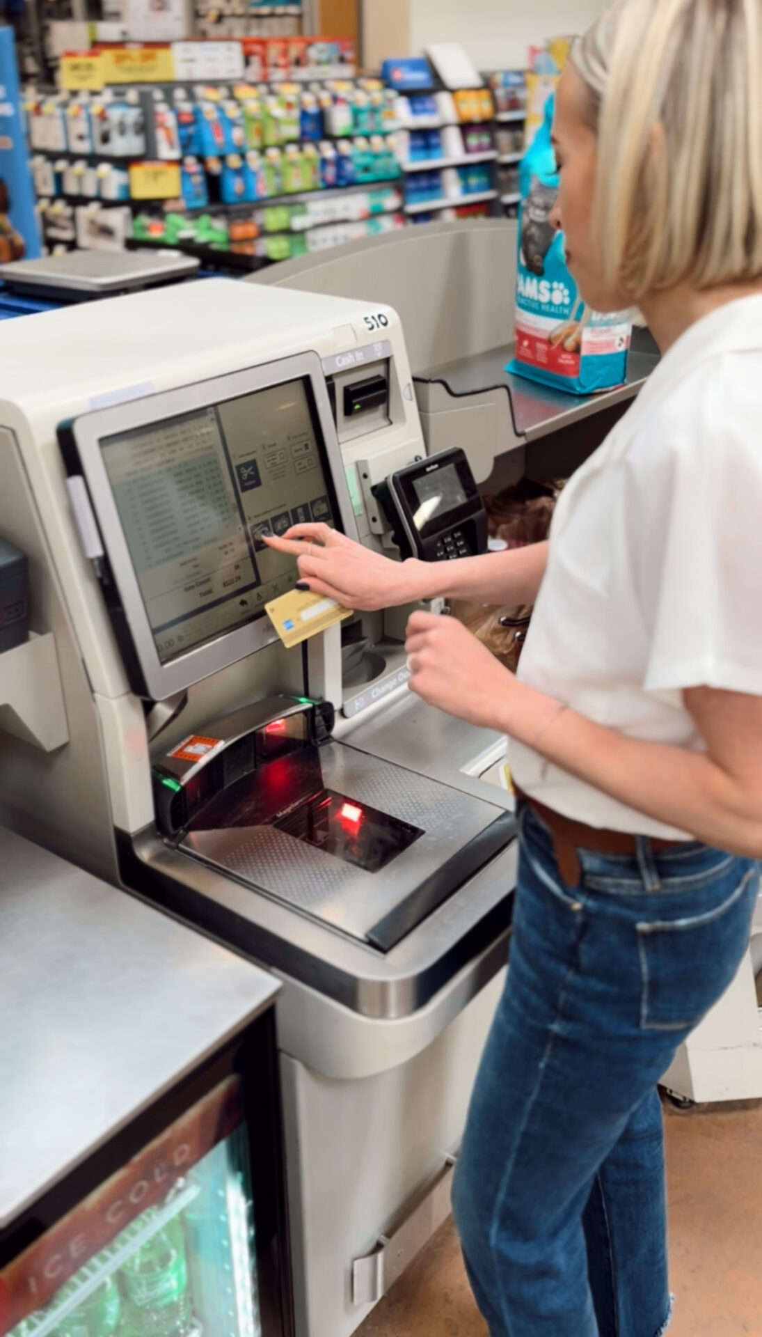 Woman using a credit card at a self-checkout kiosk while grocery shopping
